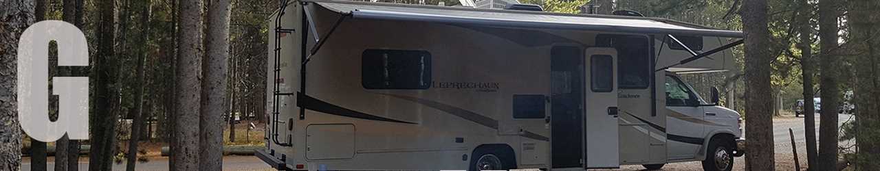 An RV with awning unfurled and door open.