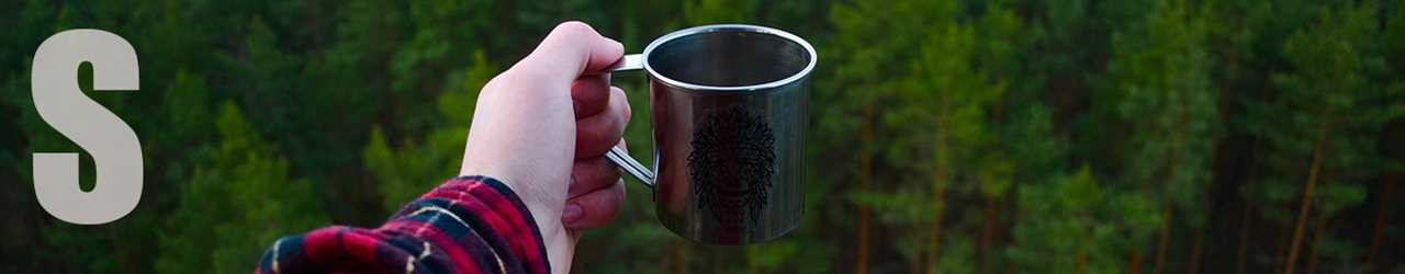 Practice good manners — A hand holds out a cup against a lush forest background.