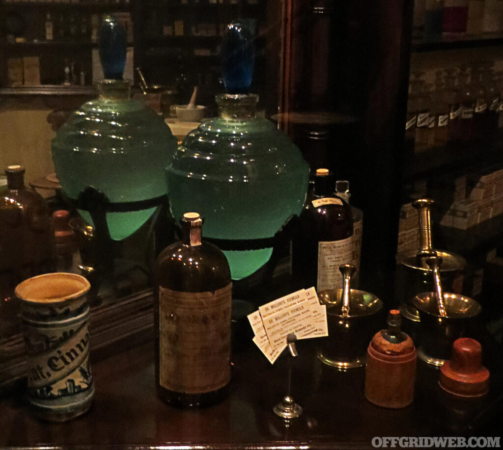 Photo of a collection of 1800's style apothecary flasks, and medicines.