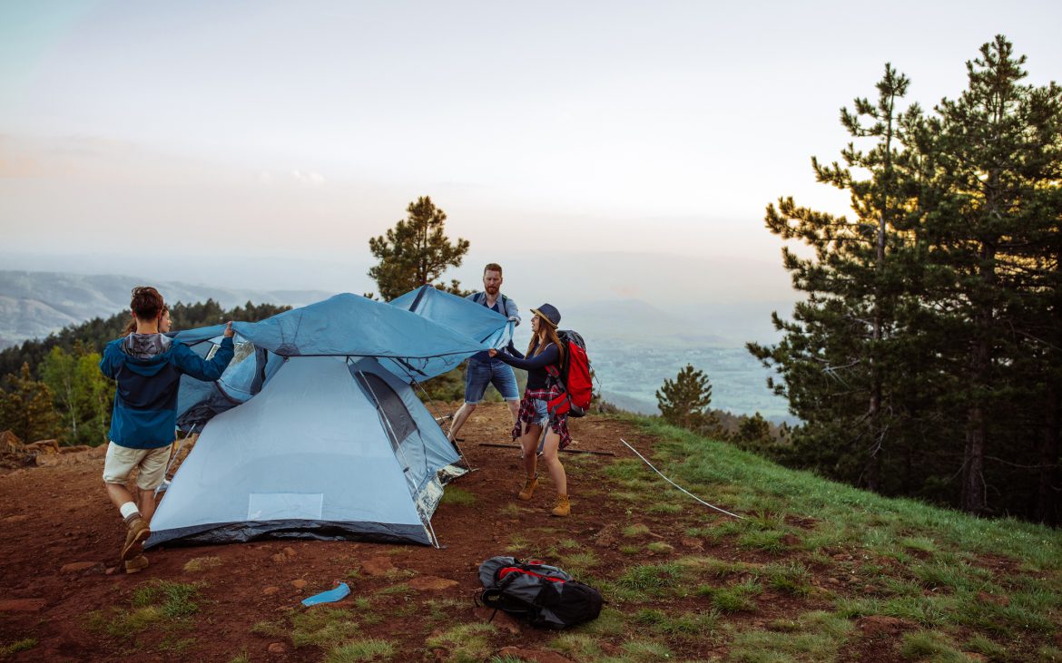 Shot of a group of friends setting up their tent while out hiking in the mountains.