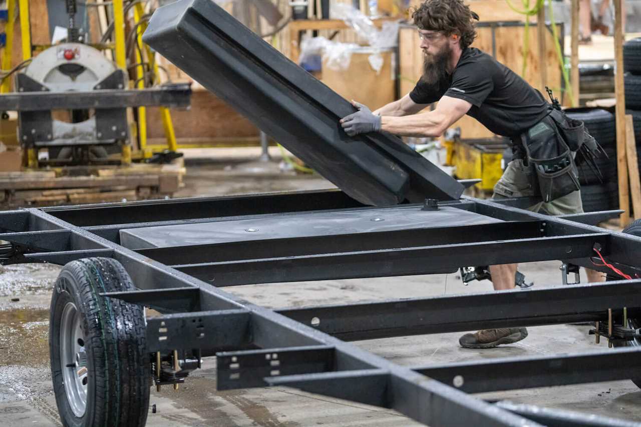 Worker installing holding tank in Coleman Lantern LT 17R trailer frame