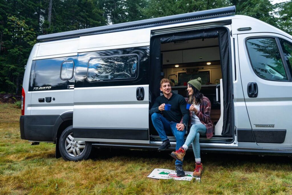 Couple sitting in their RV van drinking beverages