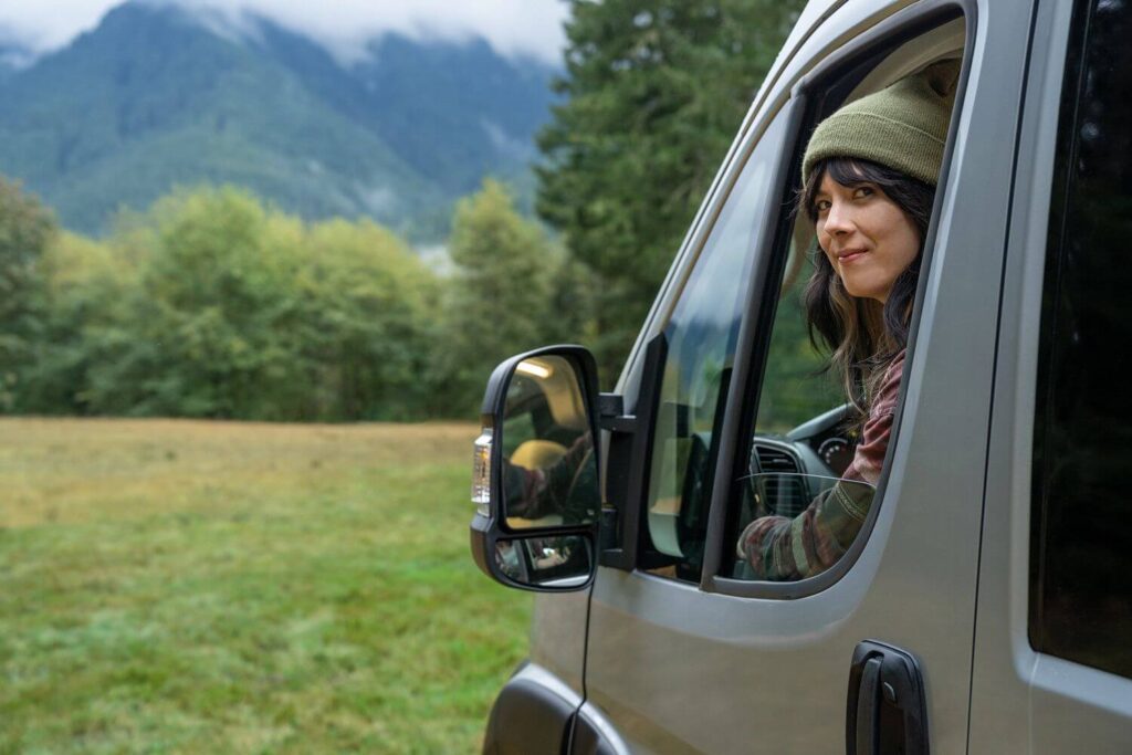 Woman leaning head out of driver's side window of Class B RV