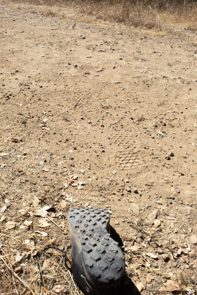 Photo of the bottom tread of a hiking shoe next to the prints it has left behind. Tracking is one method of navigating without tools.