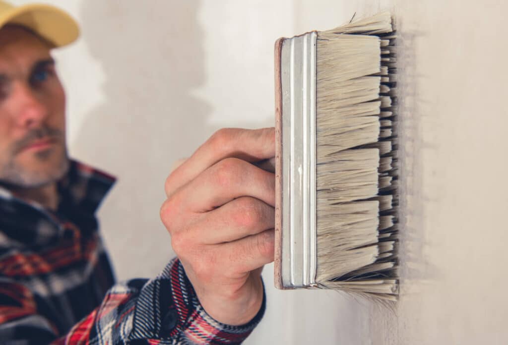 Man slowly painting a wall white