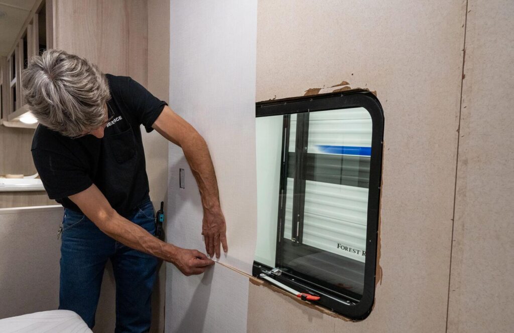 Man installing RV wallboard kit inside RV