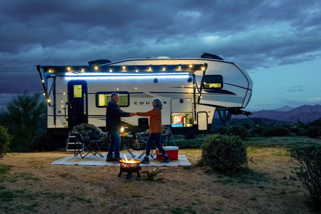 Couple dancing outside illuminated Keystone Cougar Sport 5th wheel