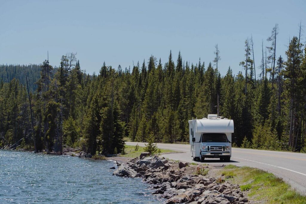 Class C RV stopped on the side of the road near a lake