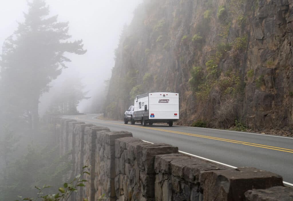 Coleman travel trailer towed along a foggy road