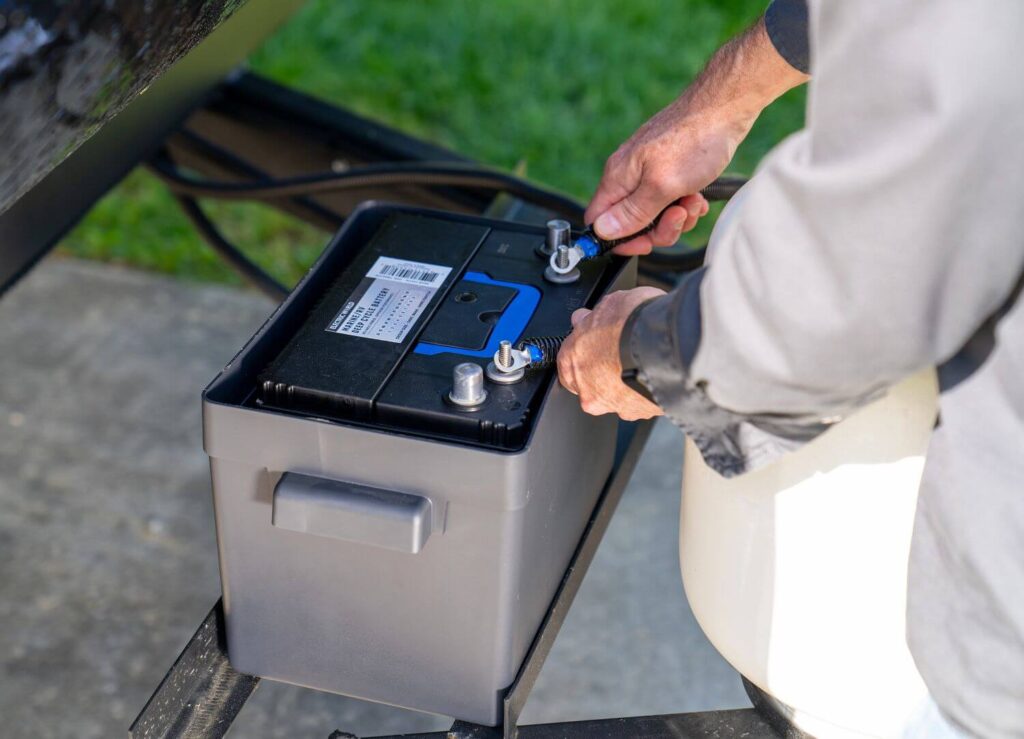 Man connecting electrical cables to RV battery