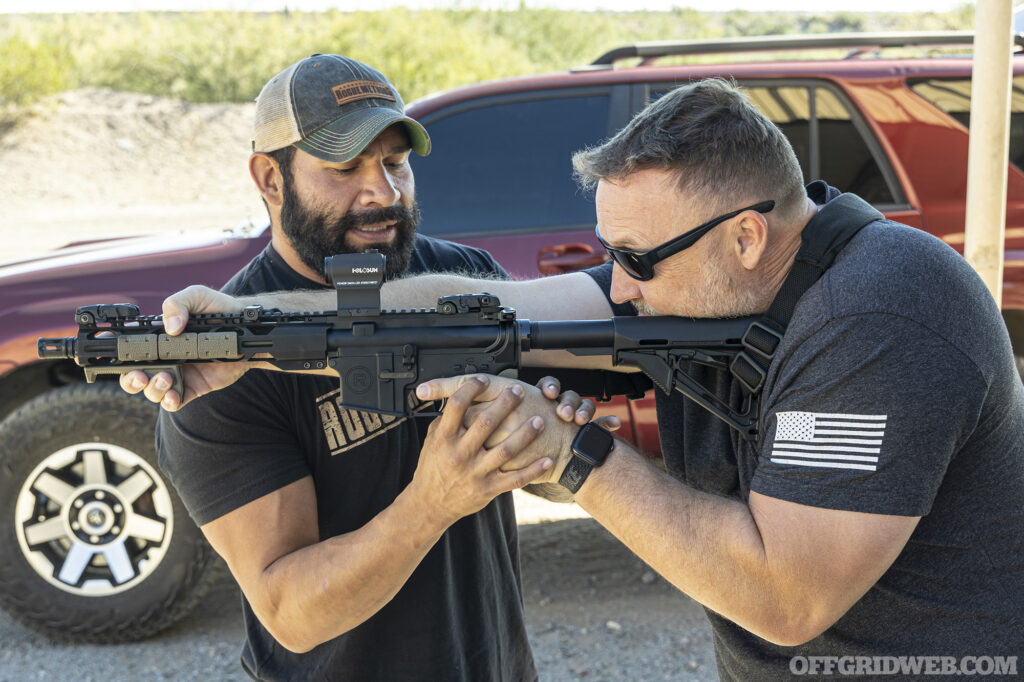 Photo of Raul Martinez Jr. instructing another student in how to properly hold an AR 15.