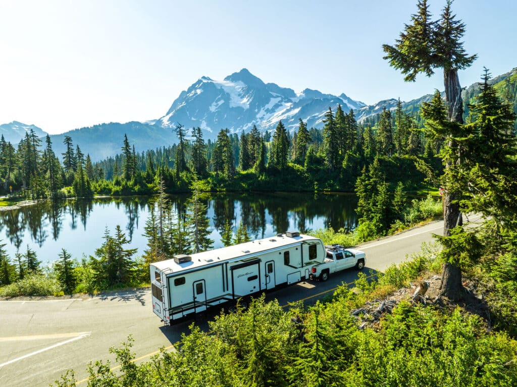 Truck towing Eddie Bauer fifth wheel with mountain background