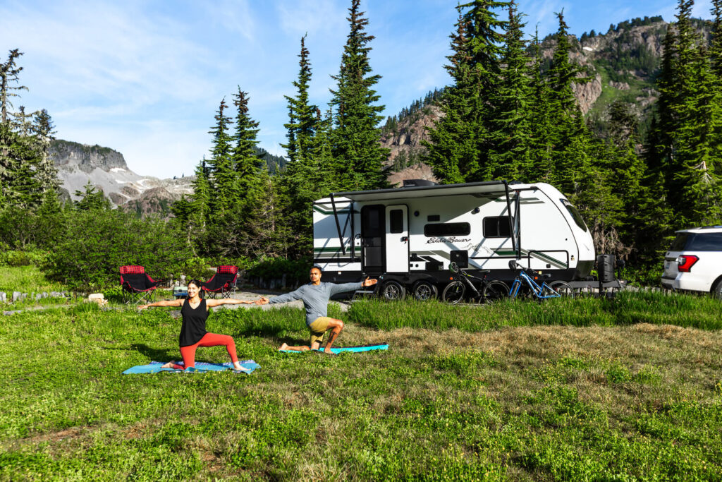 Couple doing yoga outside Eddie Bauer travel trailer