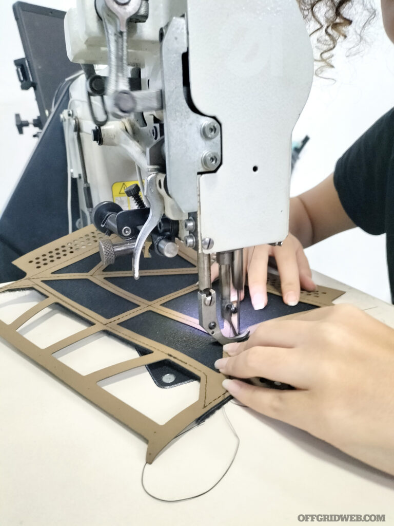 A worker at the FROG.PRO production facility sewing components for their gear.