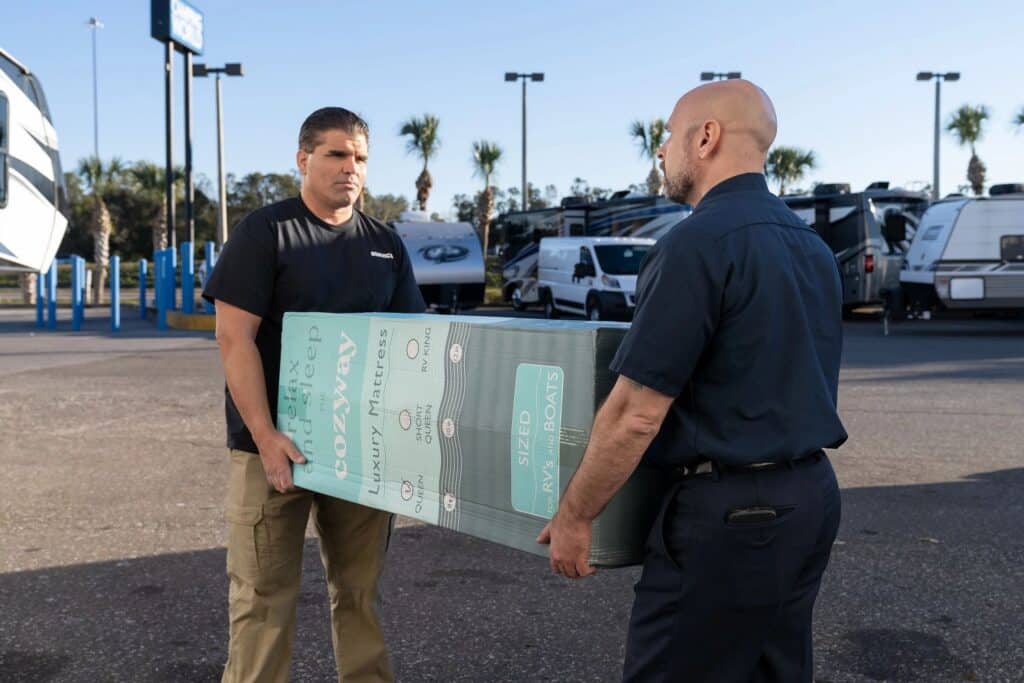 RV technicians carrying new mattress into travel trailer