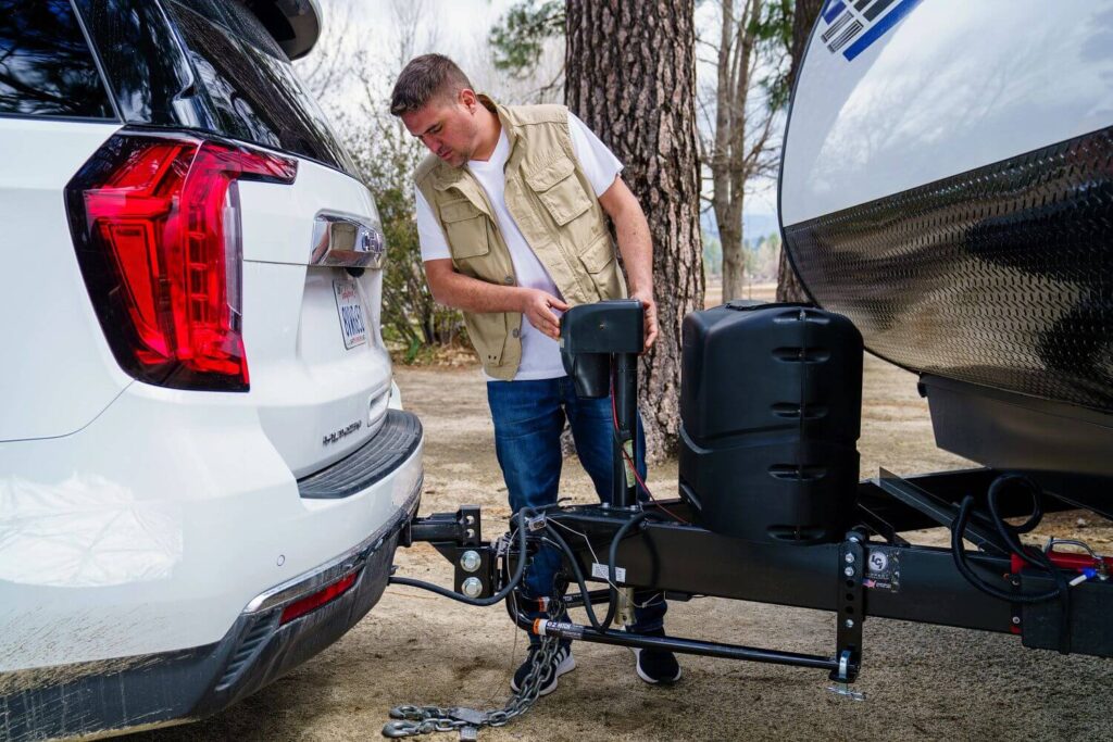 Man operating power tongue jack on travel trailer