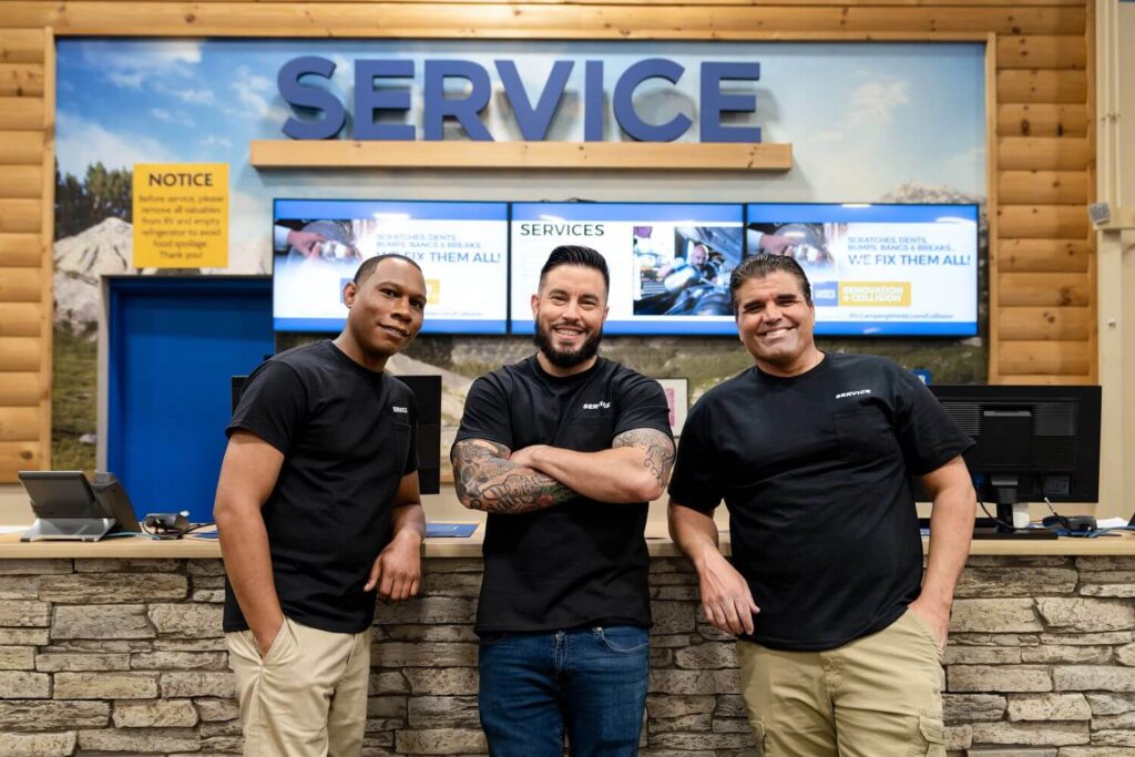 Three RV Technicians smiling in front of service desk