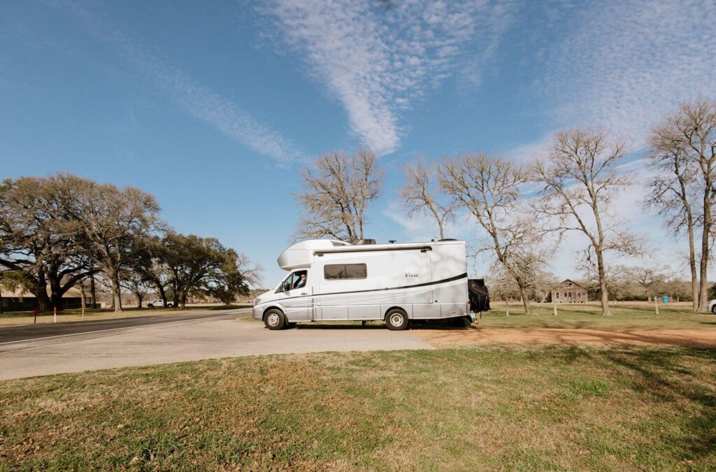 Small Class B+ RV parked in a field