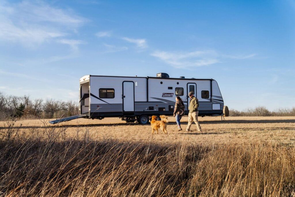Toy hauler travel trailer with couple and dog walking