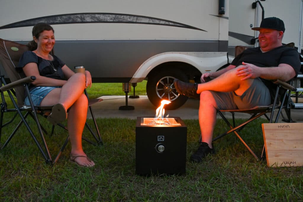 Couple sitting in camp chairs with Ukiah Qube firepit between them