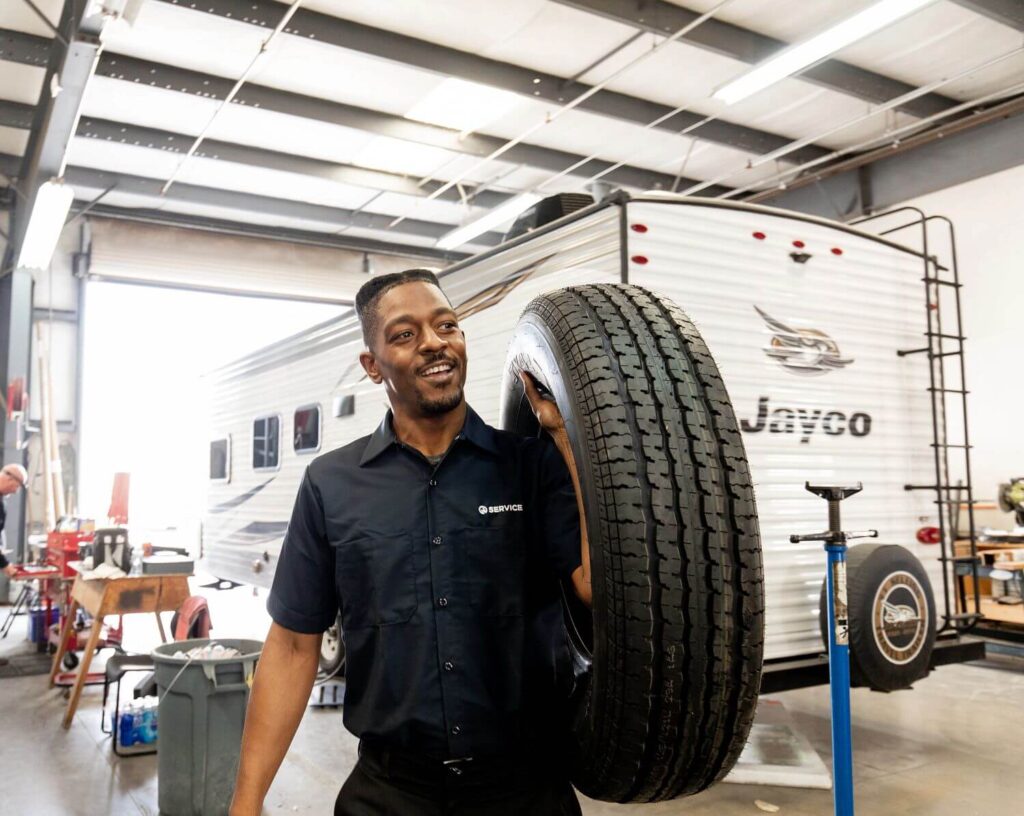 Male RV technician carrying RV tire