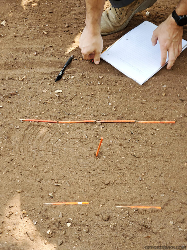 Photo of a footprint in the dust being evaluated as part of Craig Caudill's Tracking Fundamentals class.