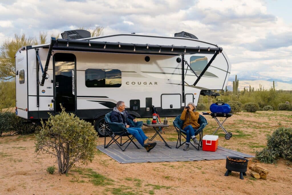 Man and woman sitting outside fifth wheel camper