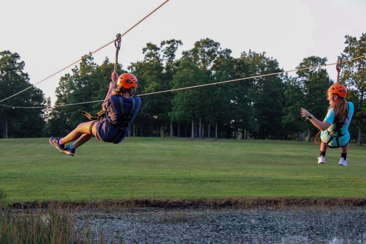 Two kids zoom down a zipline.