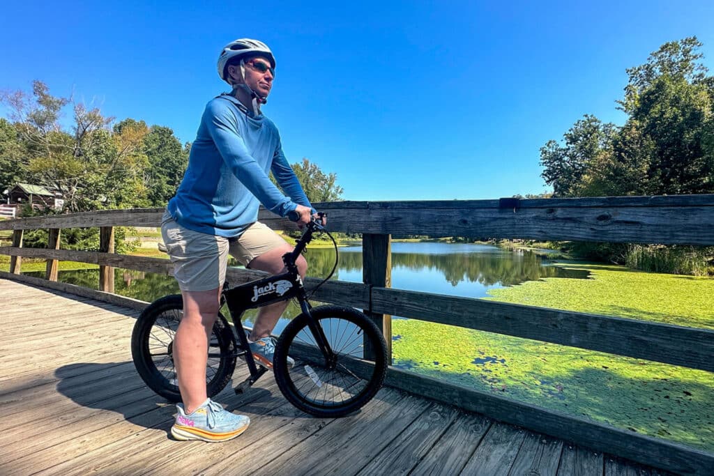 Woman standing looking over pond with JackRabbit micro ebike