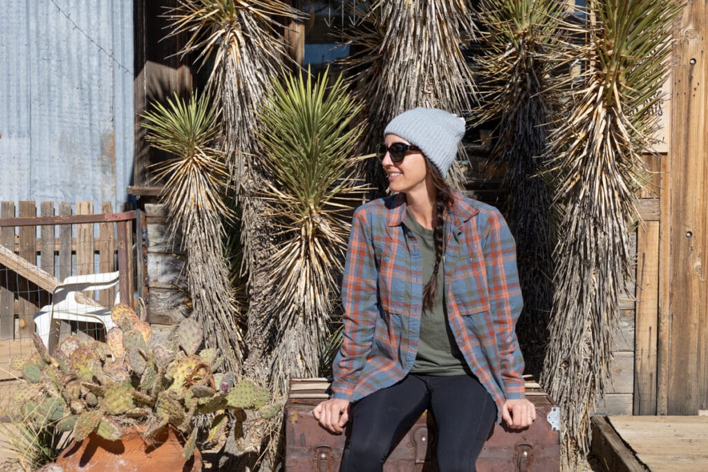 Woman sitting in front of Joshua Trees wearing fall hiking gear