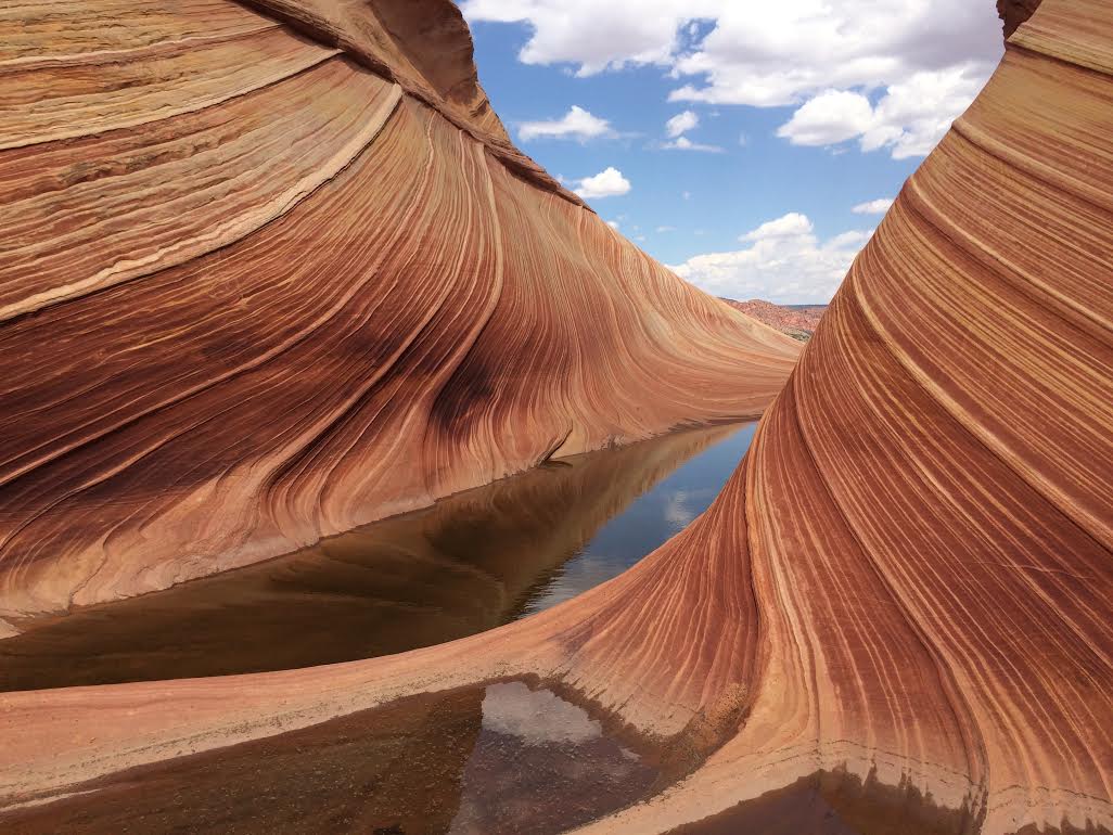 Red and white sandstone wave formation in Arizona with pools of water