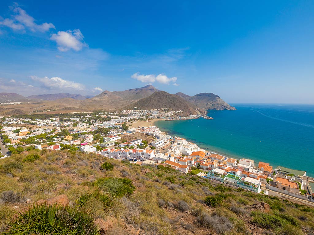 A view from a hilltop looking towards San Jose Del Cabo on a sunny day with the sea on the right of the image and a peninsula visible in the distance