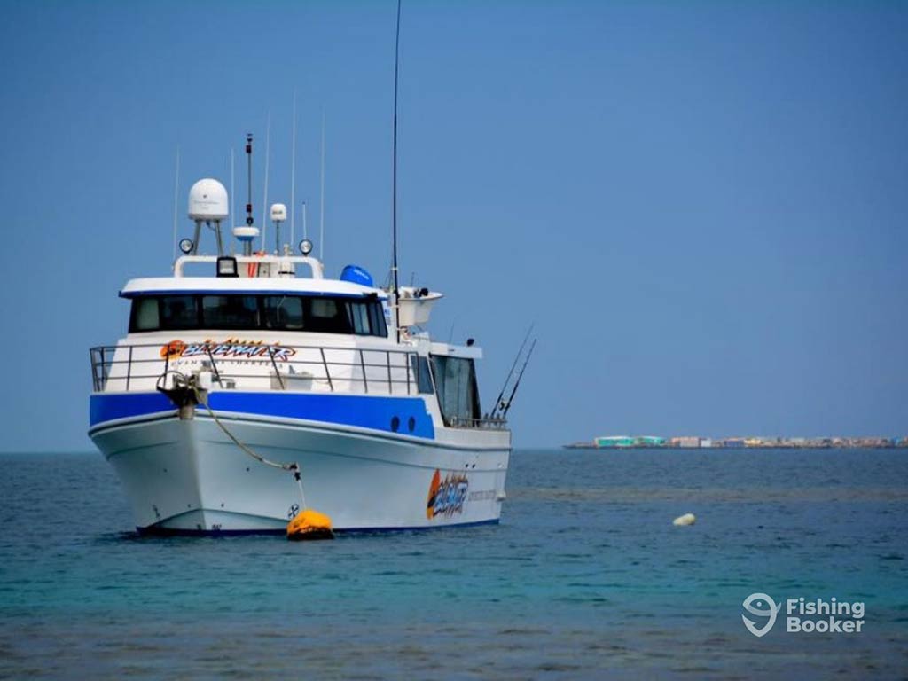 A view across the water towards a large fishing charter nearshore out of Perth on a clear day with trolling rods set up on the side of the boat