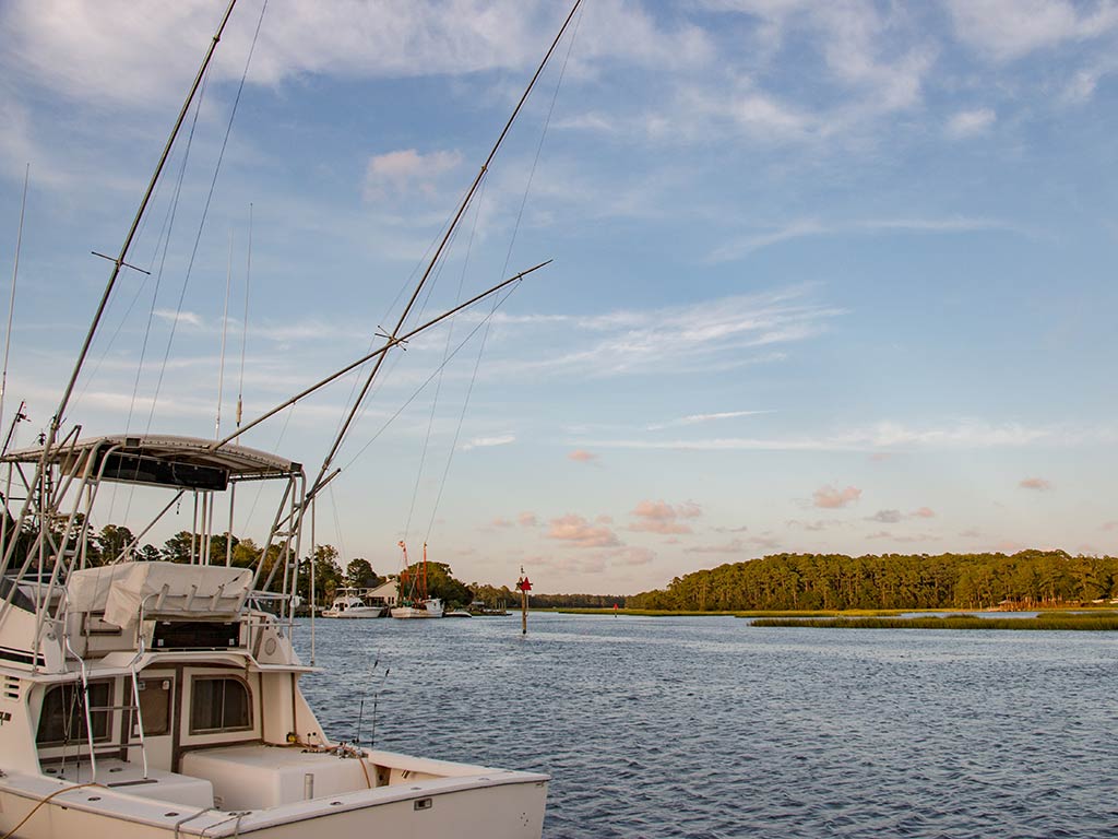 A view along the Calabash River in North Carolina on a bright day, with a fishing charter visible on the left of the image