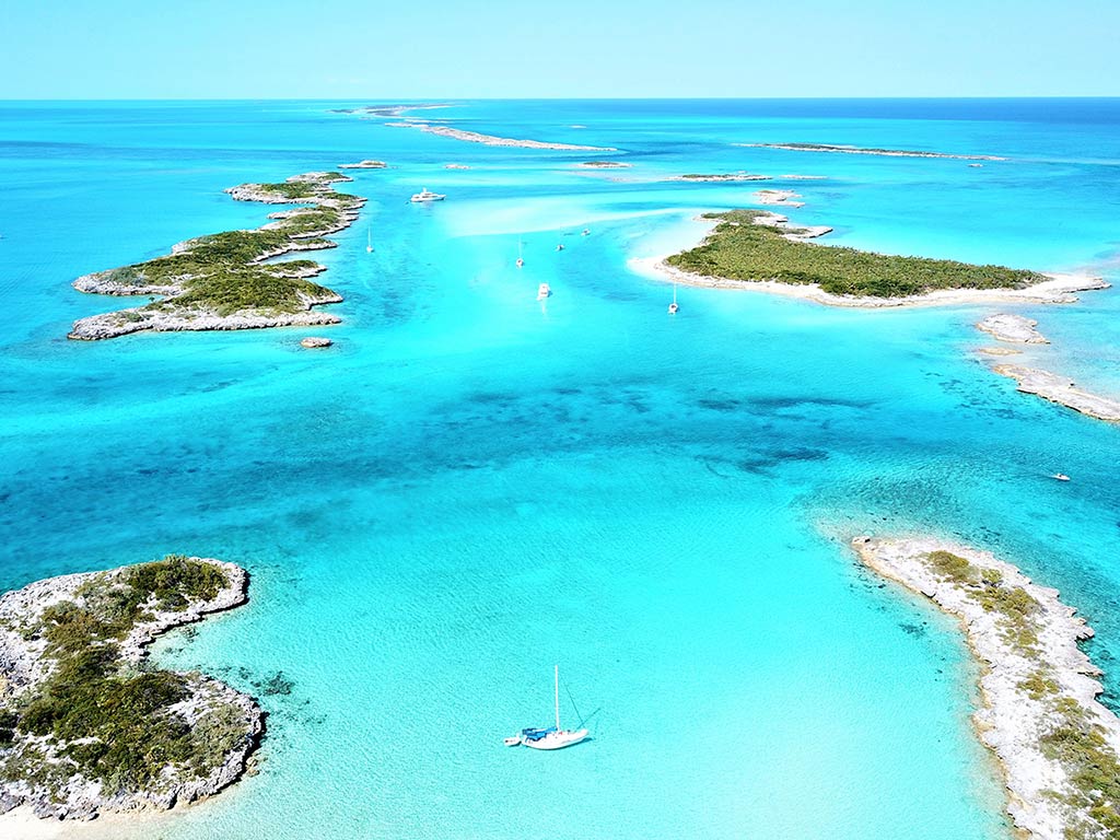 An aerial view of small islands in the crystal clear waters of the Bahamas on a sunny day