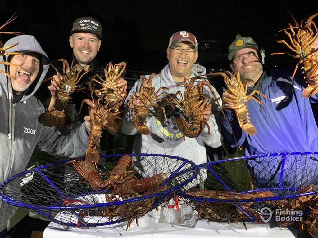 A group of anglers aboard a fishing charter in Florida at night showing off their haul of Lobster by holding some, while there are others in the nets in front of them