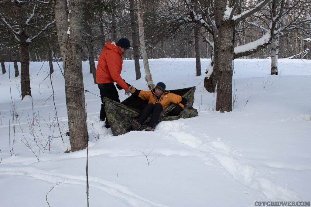 Photo of a winter survival student attempting to get in and out of a hasty shelter.