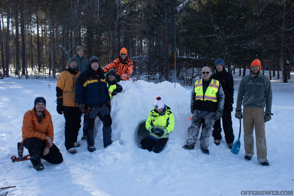 The students of the Corvus Survival Winter Survival class pose with their completed quinzee hut.