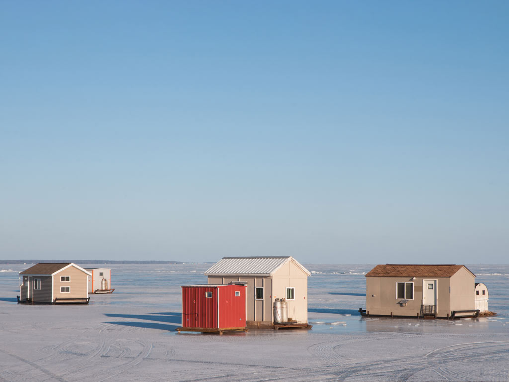 A scenic view of three ice fishing houses set up on the frozen Mille Lacs Lake near Brainerd, Minnesota, which is one of the best ice fishing destinations in the US.