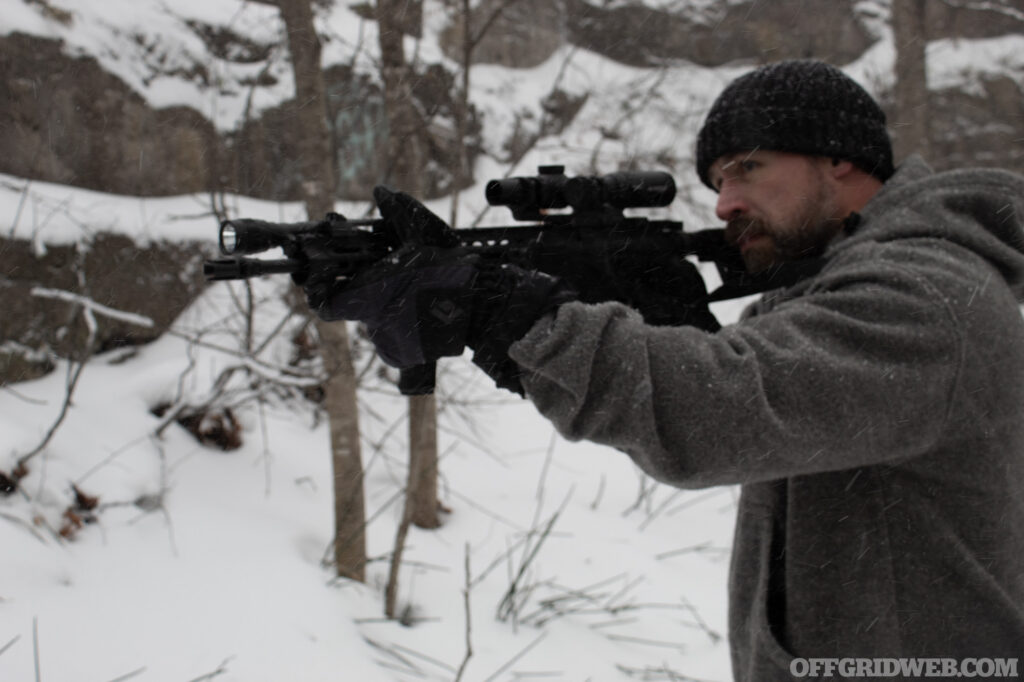 Photo of a man aiming an winter ready AR while standing in winter conditions.