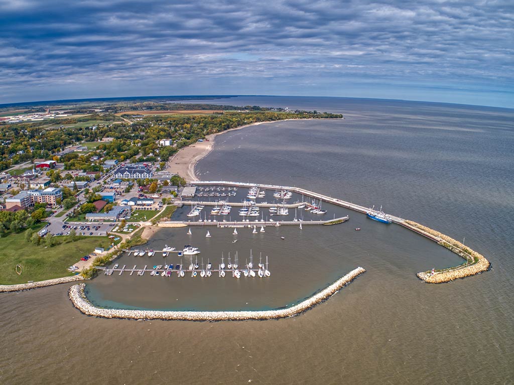 An aerial view of a marina in Gimli on Lake Winnipeg on a clear day, with murky waters visible in front of the town