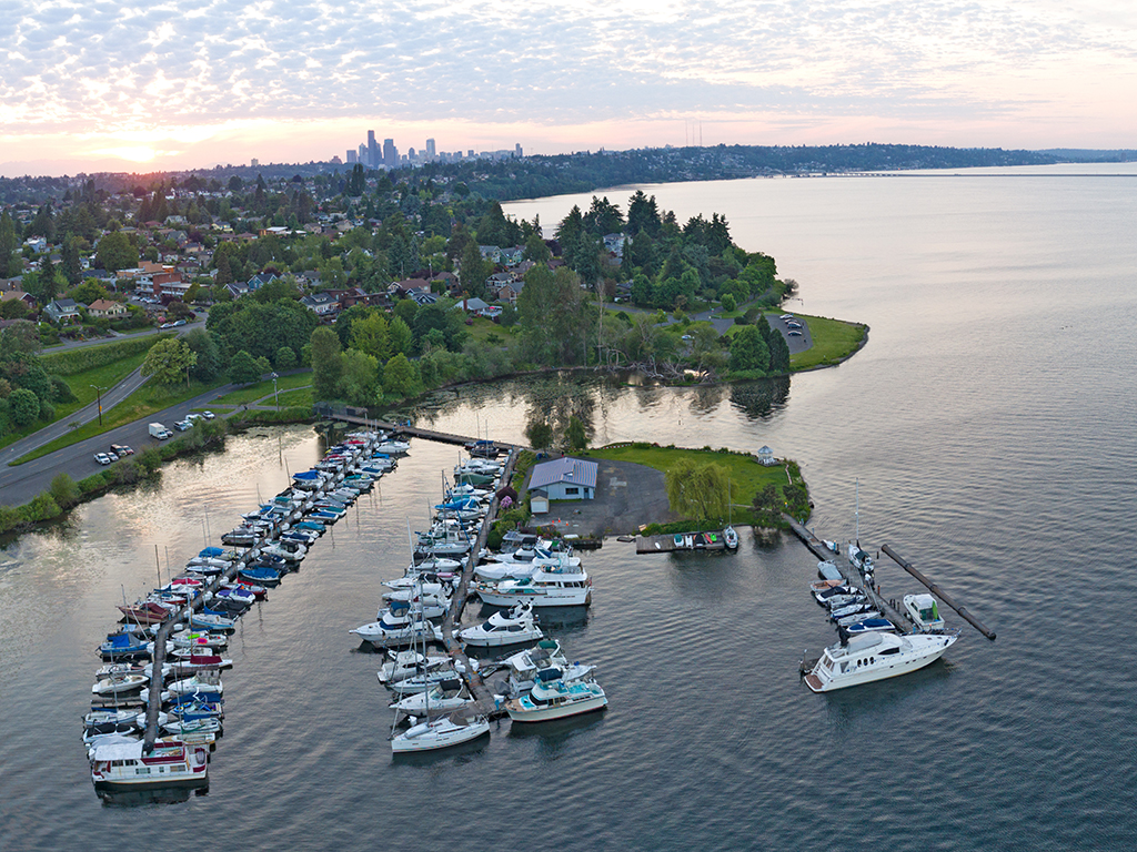 An aerial view of small marina on Lake Washington at sunset with Seattle in the background and a number of charter boats in the foreground