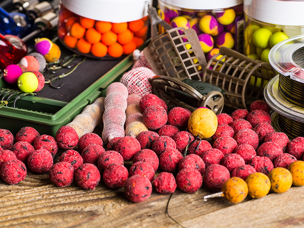 A selection of colorful boilies for Carp fishing, loose on a table with other pieces of Carp fishing equipment such as line and hooks