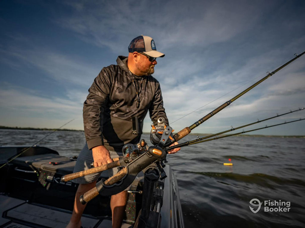 A fishing guide on a boat in Wisconsin watches three prepared medium-heavy fishing rods as he waits for a bite from a Musky