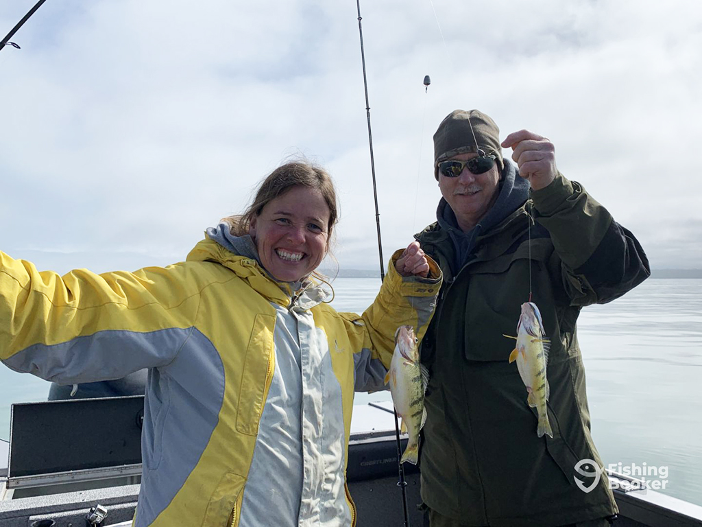 A man and a woman smile as they each hold a fishing line attached to a Yellow Perch that was caught with live bait