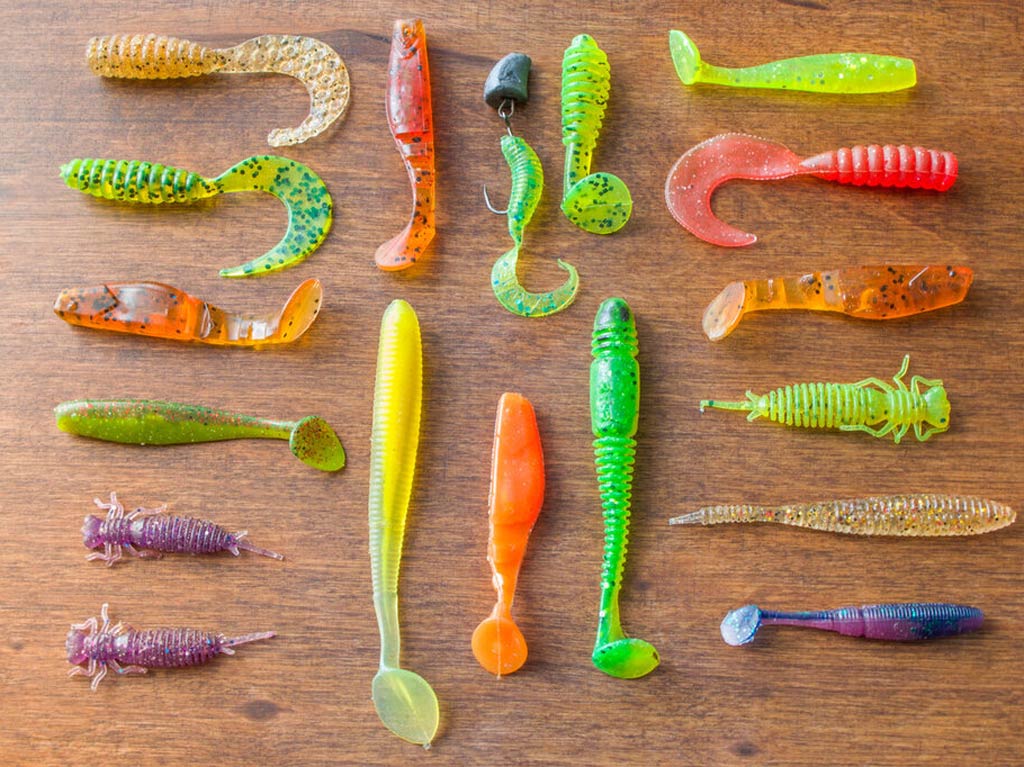 An image featuring a variety of bright colored soft plastic lures laid out on a table