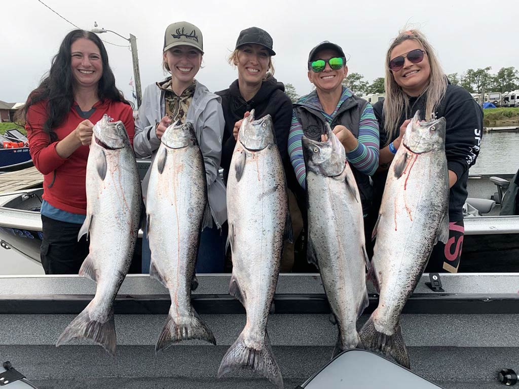 A photo of five female anglers posing with Salmon each on a Washington charter fishing boat during a cold day