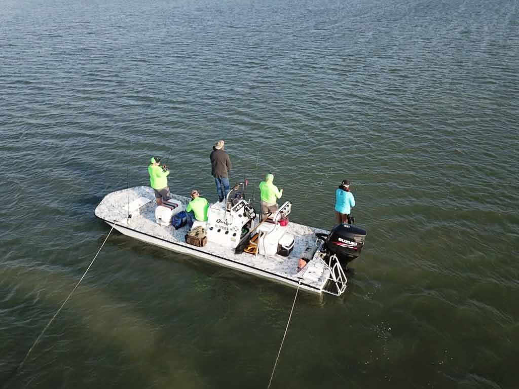 An aerial view of the anglers fishing from a boat with two drift socks tied to the side