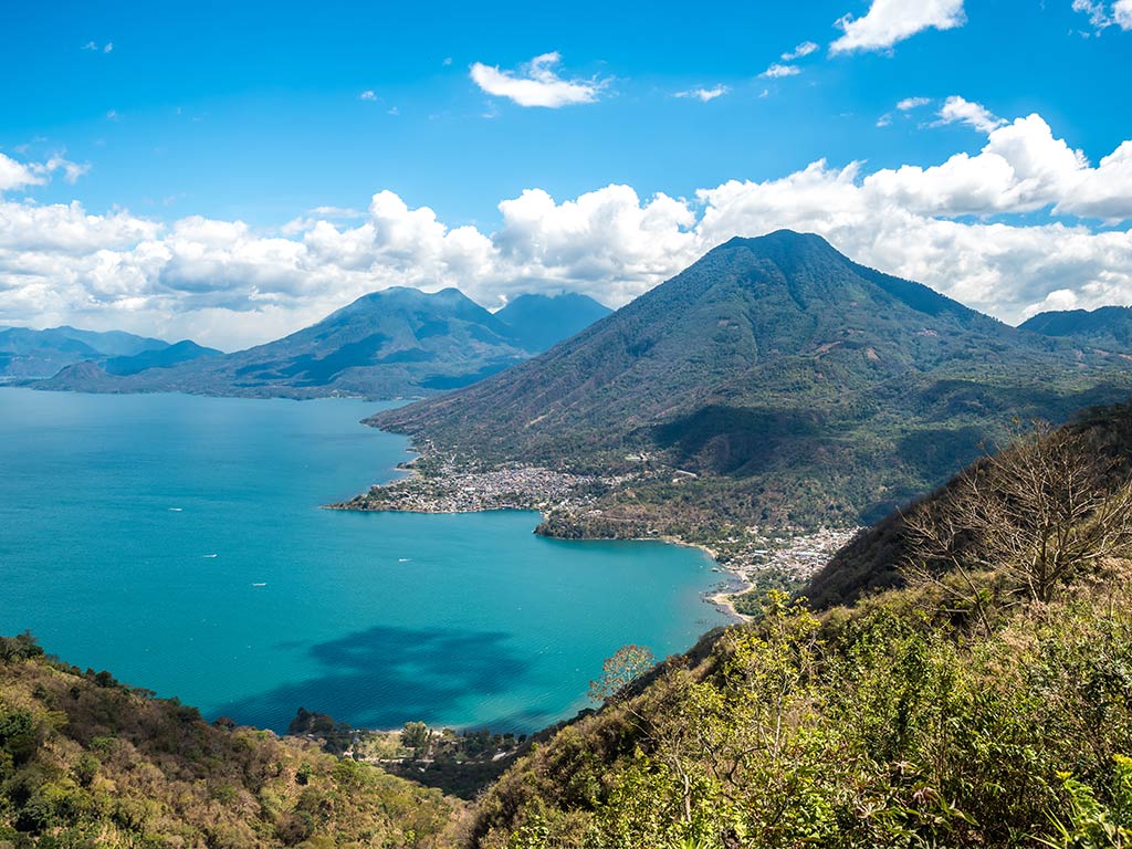 A view from a hill towards the famous Atitlán lake, with towering mountains visible on the right of the image on a clear day
