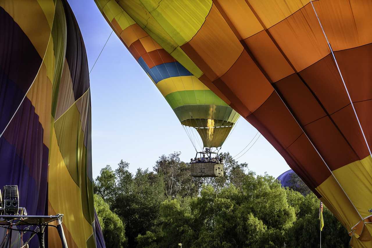 Ballon with basket filled with people coming in for a landing.